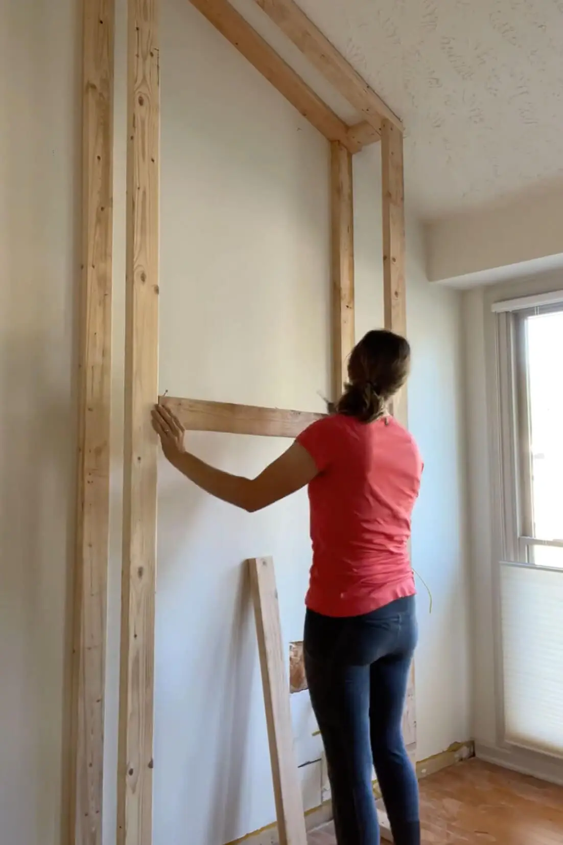 Measuring for the fireplace mantel height and adding a crossbeam to the frame.